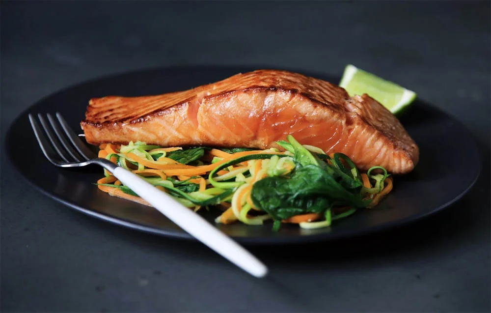 ماهی سالمون سرخ شده داخل بشقاب همراه با سبزیجات