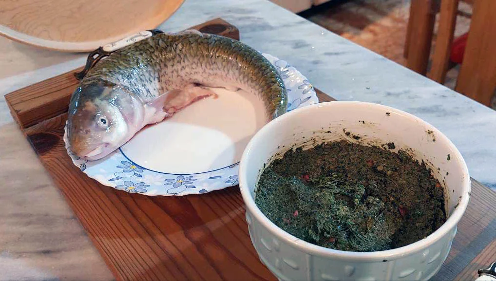 ماهی و مواد داخل شکم ماهی شامل سبزی ماهی شکم پر و رب انار و سایر مواد اولیه